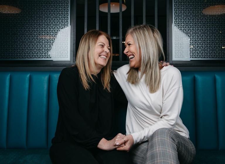 Two women sitting holding hands