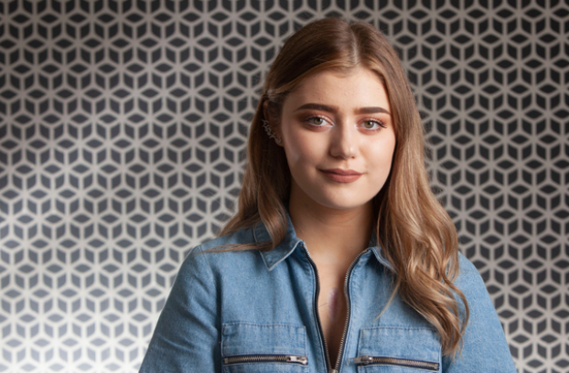 young girl smiling in front of patterned wallpaper